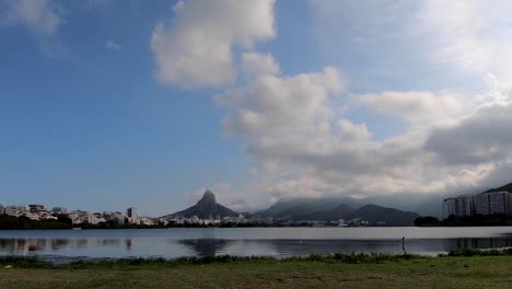 time lapse slowly zooming in on fast moving clouds above the city lake in rio de janeiro with the two brothers mountain peaks in the background against a blue sky