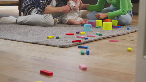 familia transgénero con bebé jugando con juguetes coloridos en el salón en casa