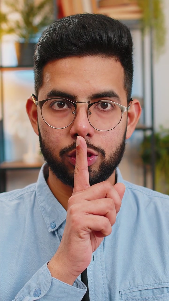 L'uomo indiano preme l'indice sulle labbra fa silenzio gesto silenzio per favore smettila di parlare pettegolezzi a casa