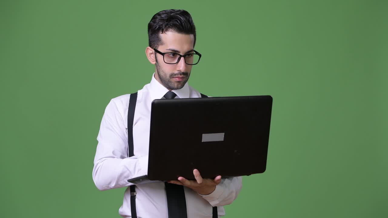 joven empresario persa barbudo y guapo contra un fondo verde