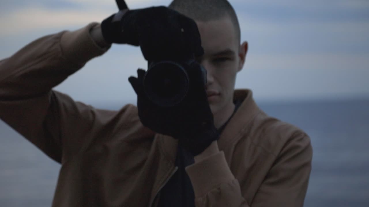 Man Taking Pictures. Man Holding, Lifting Camera And Composing A Shot With Blurred Ocean And Sky On The Background. - close up shot
