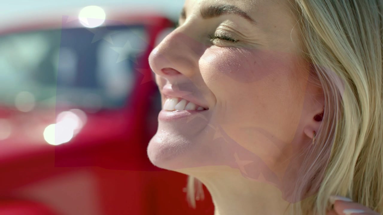 Donna che alza la mano, spostando i capelli, mettendo in mostra anelli e orologio accanto a un'auto rossa sfocata per una pubblicità automobilistica.