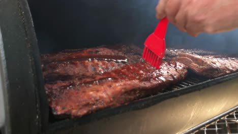 racks of ribs having sauce applied in an off set smoker