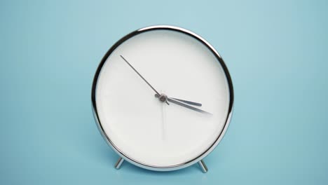 black alarm clock isolated on a blue background,time starts walking at 3 o'clock.