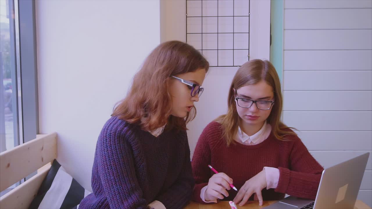 dos mujeres jóvenes estudiando en un café