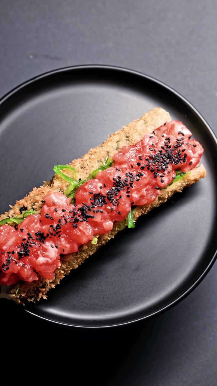Piatto fresco servito su un piatto nero con frutti di mare e guarnizioni in un ristorante moderno di sera