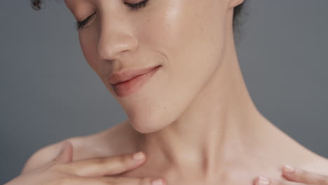 close up portrait beautiful mixed race woman touching soft skin with hand caressing smooth healthy complexion enjoying natural skincare gorgeous feminine beauty concept on grey background