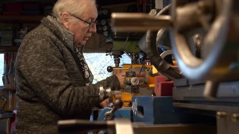 hombre maduro ingeniero mecánico montando una máquina de torno en el taller