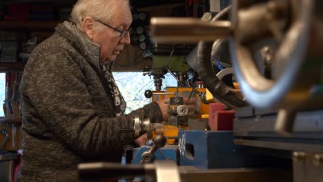 mature man mechanical engineer setting up a lathe machine in workshop