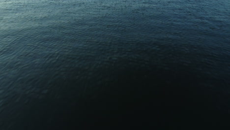 drone flying low to water to reveal horizon