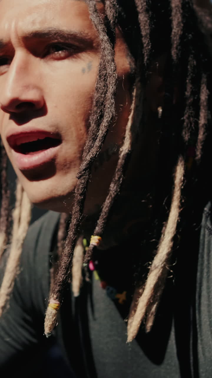 Ritratto in primo piano di un uomo con i dreadlock e tatuaggi sul viso