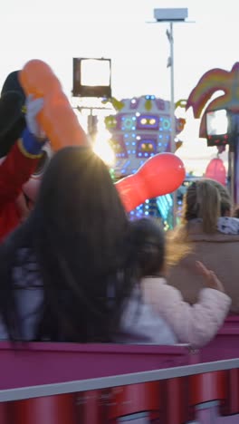 costume character on a fairground ride with balloons at sunset