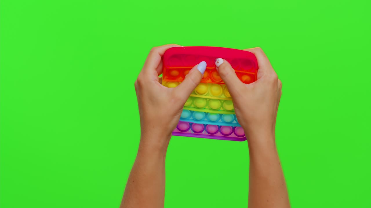 las manos de una persona están sosteniendo un juguete de arco iris pop it fidget.