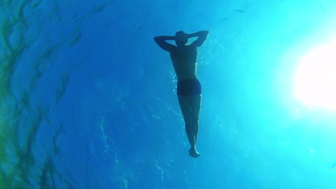 Relaxed man floating in the deep blue sea under the sun