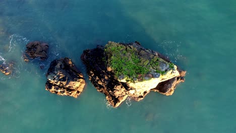 Drohne-Fliegt-Von-Einer-Kleinen-Insel-Hoch-Und-Enthüllt-Kiesstrand-Und-Klippen