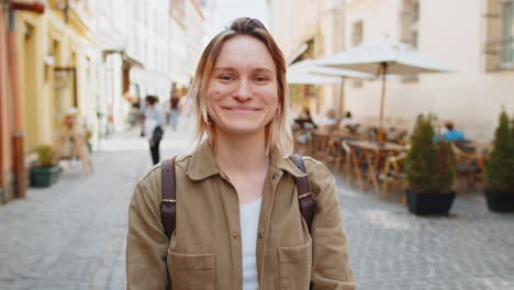 portrait of happy young smiling woman tourist looking at camera resting outdoors on city street