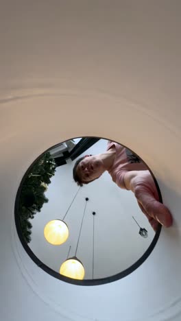 person looking down into a round hole in a white ceiling