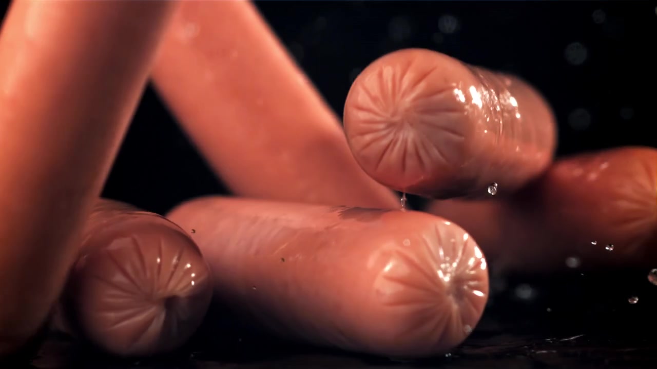 Pølser falder i slow motion med vandplask på sort baggrund