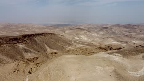 aerial forward slow and calm drone shot of an empty hills in the arad,israeli desert, blue sky on a sunny day