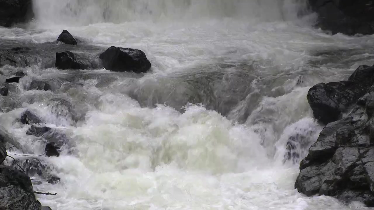 Rushing Water Cascading Over Dark Rocks in a Mountain Stream
