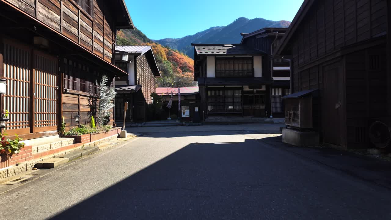 Scenic view of historic wood buildings in Narai-Juku, surrounded by vibrant autumn foliage.