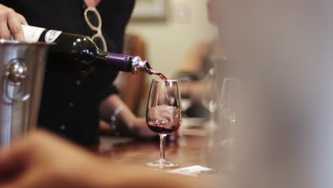bartender pours a glass of red wine at the bar counter. people love wine concept