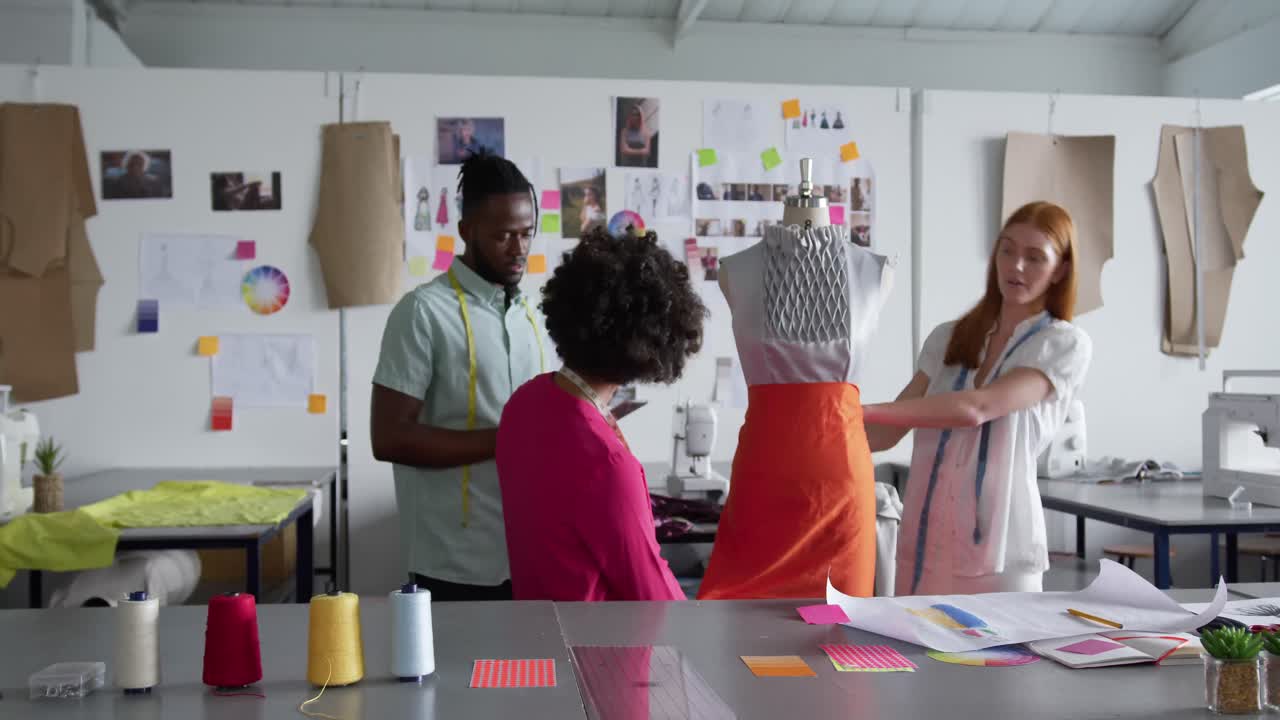 tres colegas vistiendo a un modelo en la oficina de moda