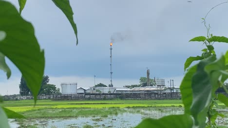 a gas plant complex with a tall chimney burning gas