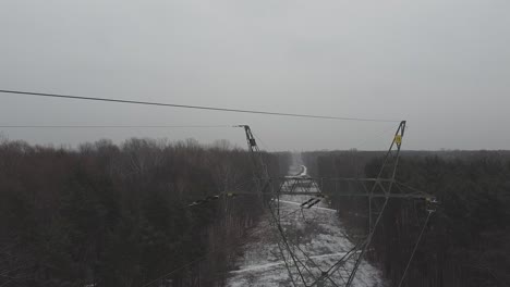 drone video of going up among power lines in a snowy forest