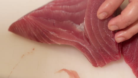 sharp knife used in slicing raw meat of fresh tuna fish for preparing sushi in a japanese restaurant - close up, slow motion