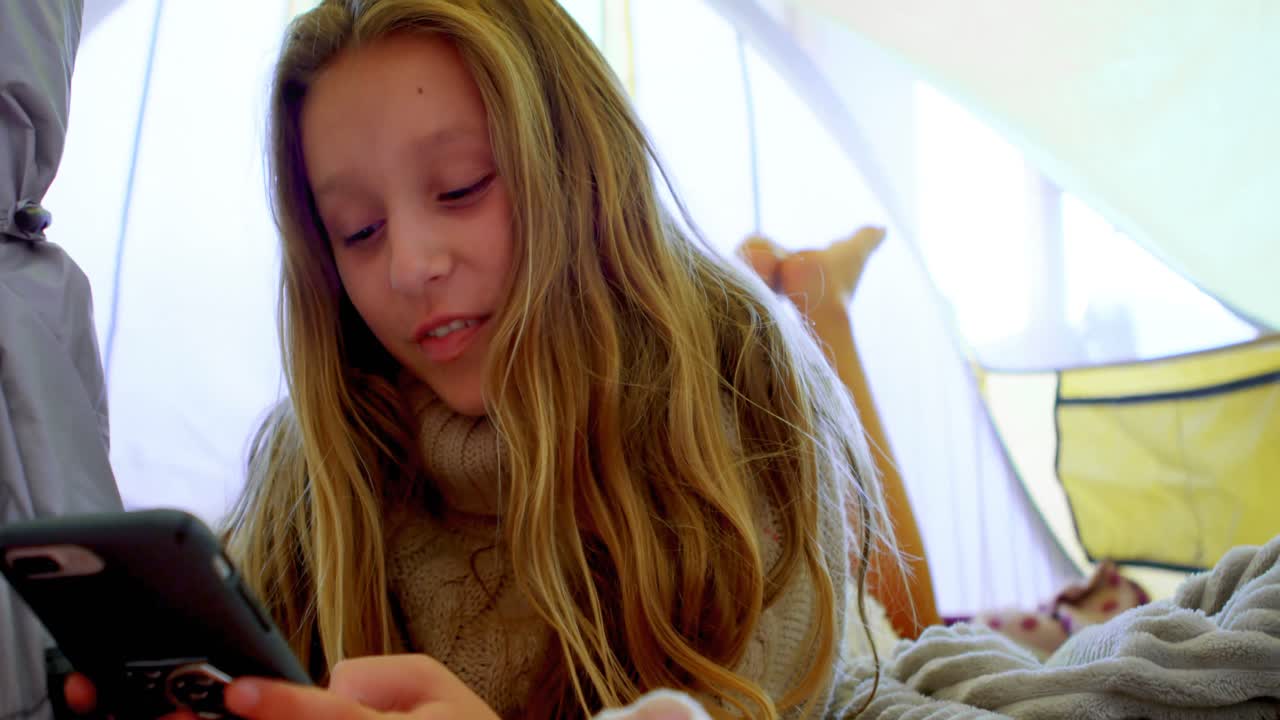 텐트 4k에서 휴대 전화를 사용하는 소녀