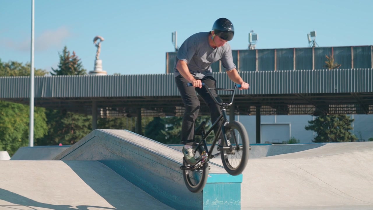 Giovane uomo su una bici BMX che esegue un trick manuale in uno skatepark.