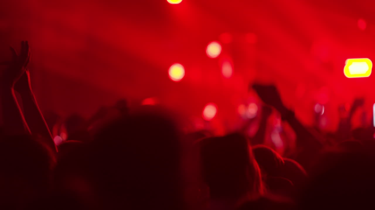 Silhouette di persone che ballano a un concerto musicale vibrante con luci rosse