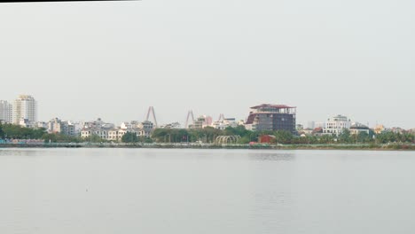 Distant-shoreline,-residents-commute-to-unknown-destinations,-still-water