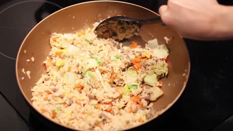 stirring and flipping fried rice in a pan