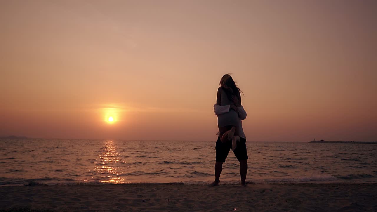 소녀의 실루은 달리고 뛰어다니며 바다에서 남자를 포옹합니다. 느린 동영상
