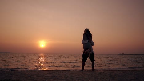 girl silhouette runs and jumps hugs man at sea slow motion