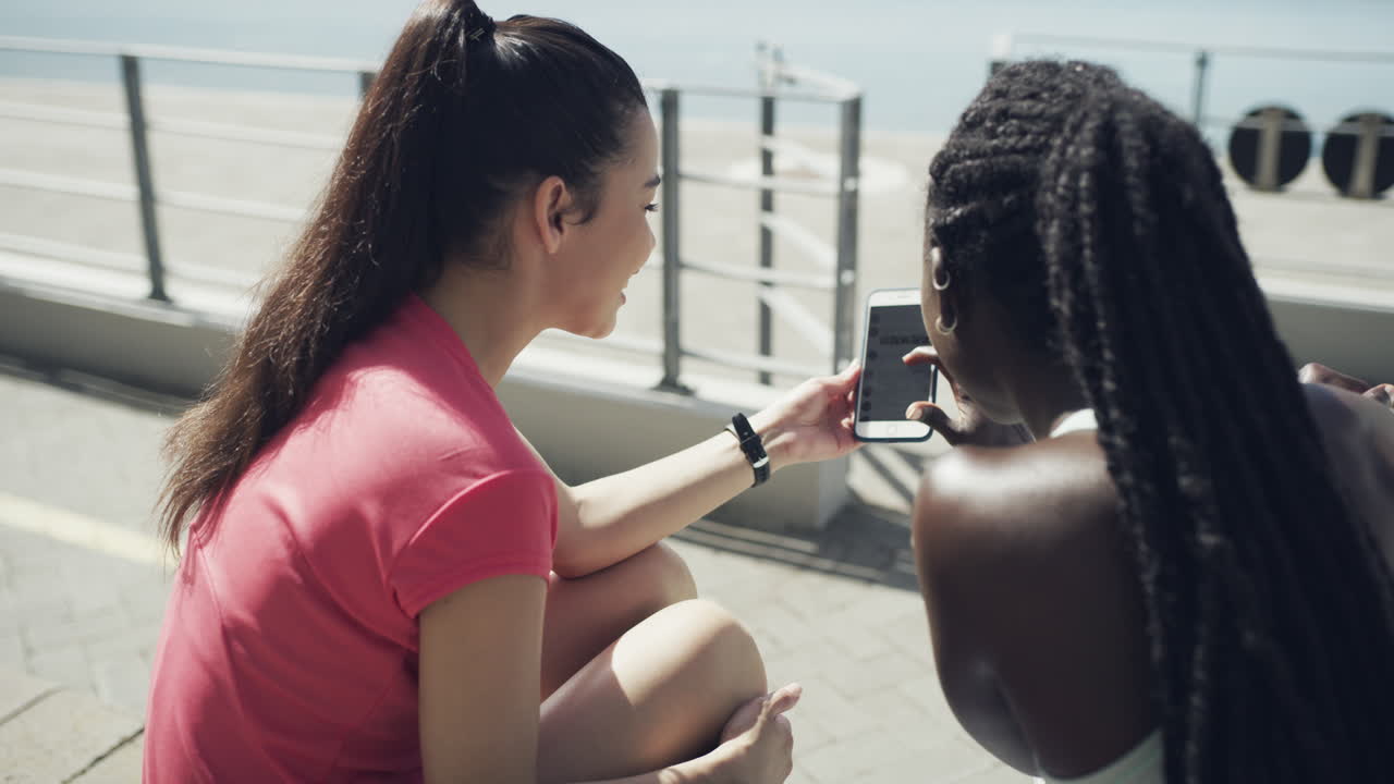 two friends together using a smartphone outside
