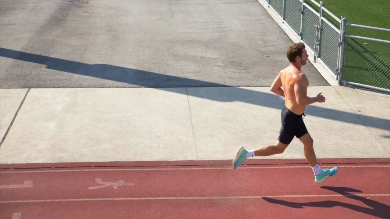 hombre guapo con cuerpo muscular corriendo en una pista deportiva
