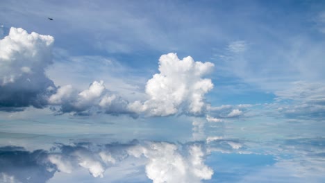 futuristic background consisting of time lapse clip of white fluffy clouds over blue sky and their reflection, video loop