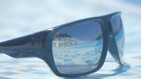 gafas de sol en la playa con fondo de mar azul, verano. vista lateral, enfoque selectivo. concepto de sueños de viajero - reflexión sobre gafas de sol.