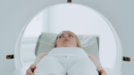 retrato en primer plano de una paciente acostada en una tomografía computarizada o resonancia magnética, la cama se mueve dentro de la máquina escaneando su cuerpo y cerebro. en un laboratorio médico con equipos de alta tecnología. se mueve más cerca de la cámara.