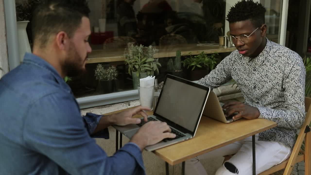 Young men working with laptops in cafe