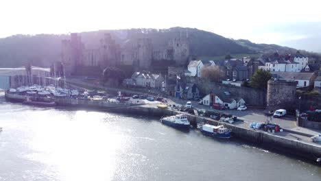 idyllic conwy castle and harbour fishing town boats on coastal waterfront aerial slow push in