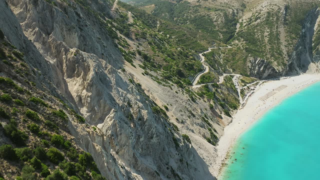 Drone flyover forested rocky cliffs revealing pristine turquoise water in the Myrtos Beach, Greece
