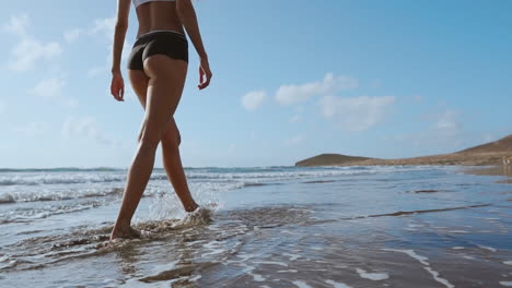 Frau-Läuft-Barfuß-Am-Sommerstrand.-Nahaufnahme-Des-Beins-Einer-Jungen-Frau,-Die-Am-Strand-Entlang-Einer-Welle-Aus-Meerwasser-Und-Sand-Läuft.-Reisekonzept.