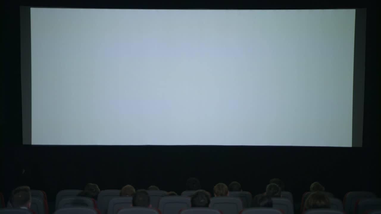 Large white screen in cinema. Beginning film in cinema. Cinema screen people