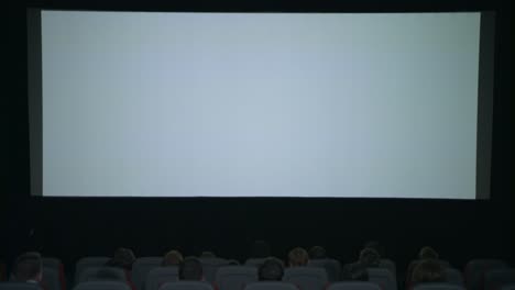 gran pantalla blanca en el cine. comienzo de la película en el cine. gente de la pantalla del cine