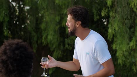 man laughing and enjoying wine at an outdoor social gathering
