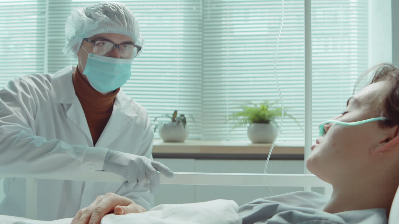 여성 환자가 병원 병실에서 마스크를 쓴 의사와 이야기하고 있습니다.